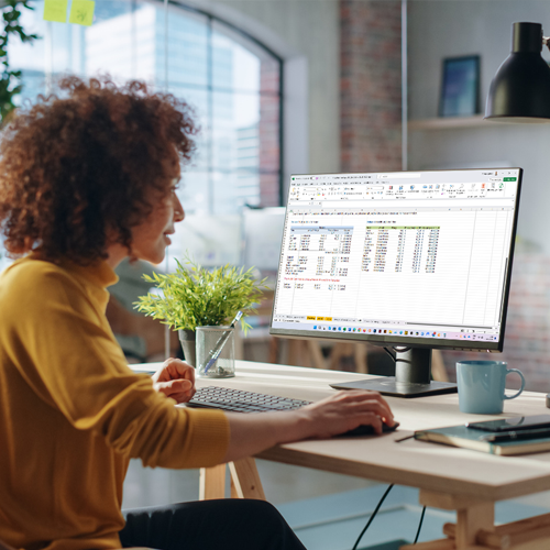 Bild: Eine junge hübsche Frau sitzt am PC im gut gestylten Büro und arbeitet mit Excel