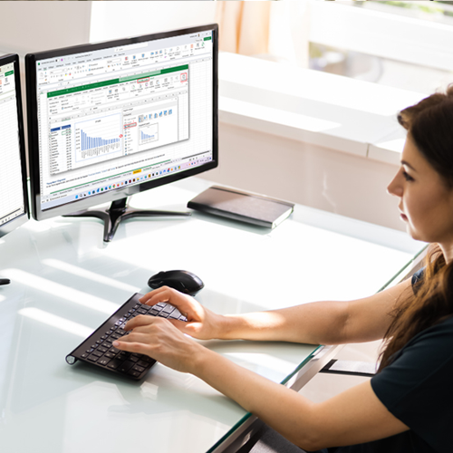 Bild: Junge Frau arbeitet am Computer und erstellt eine Pivot Tabelle in Excel